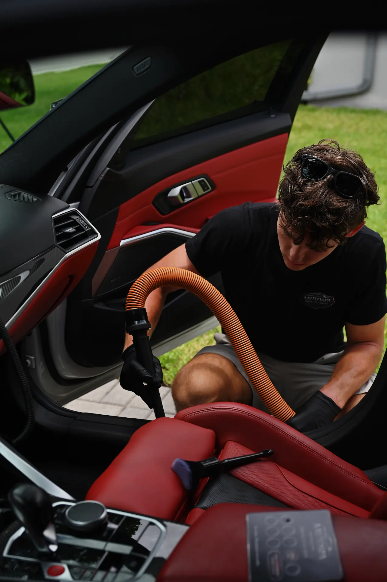 AAutospa detailer deep-cleaning a red leather car interior
